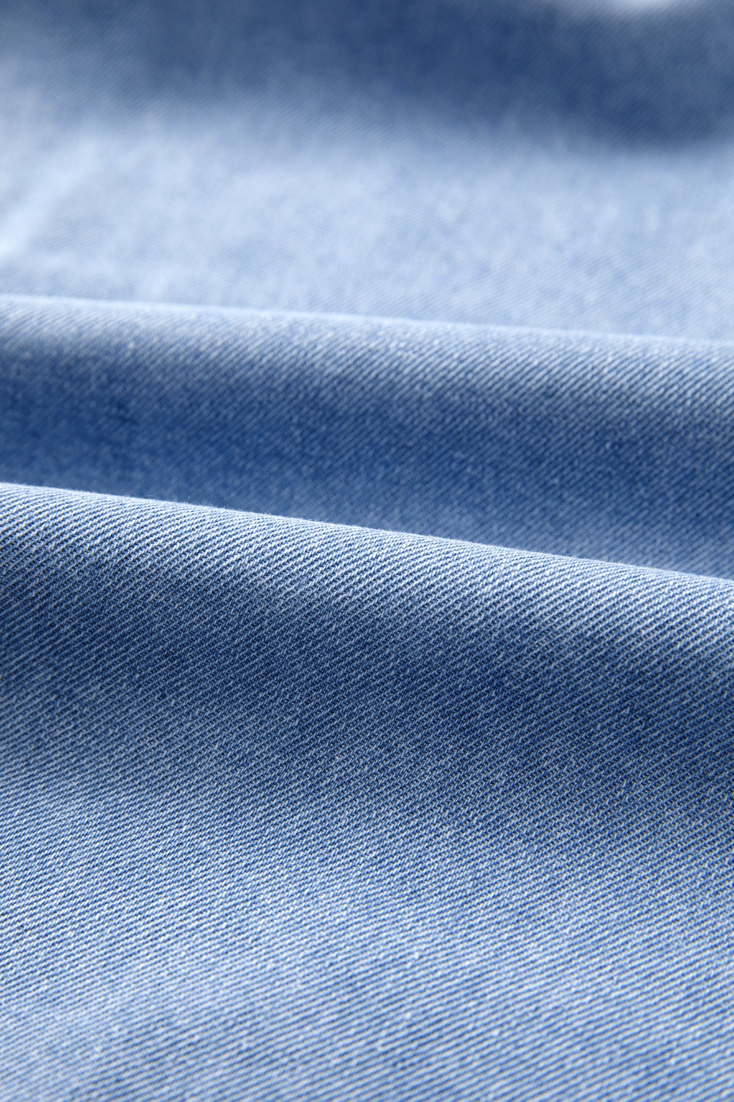 Light blue distressed denim fabric with soft folds and texture.