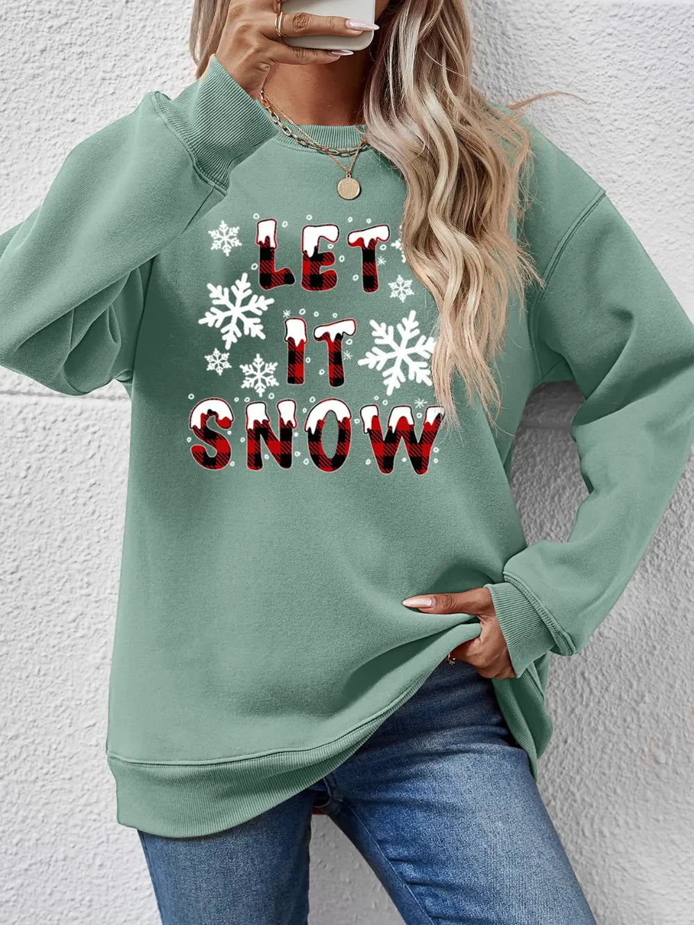 Sage green crewneck sweatshirt with "Let It Snow" graphic and snowflakes.