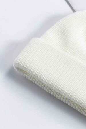 White ribbed knit beanie with a turn-up cuff, acrylic material.