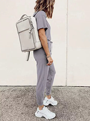 Grey casual round neck top and jogger pants set with drawstring waist, styled with white sneakers and backpack.