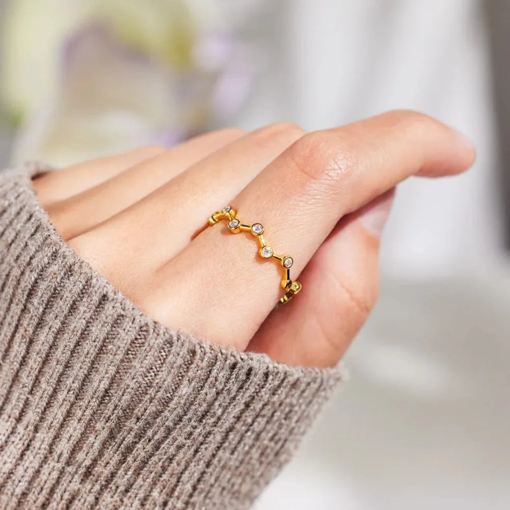 Gold celestial ring with clear zirconia accents on a finger.