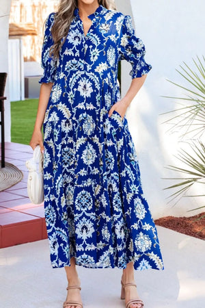 Vibrant floral maxi dress with frilled collar, buttoned front, puff sleeves, and pockets.