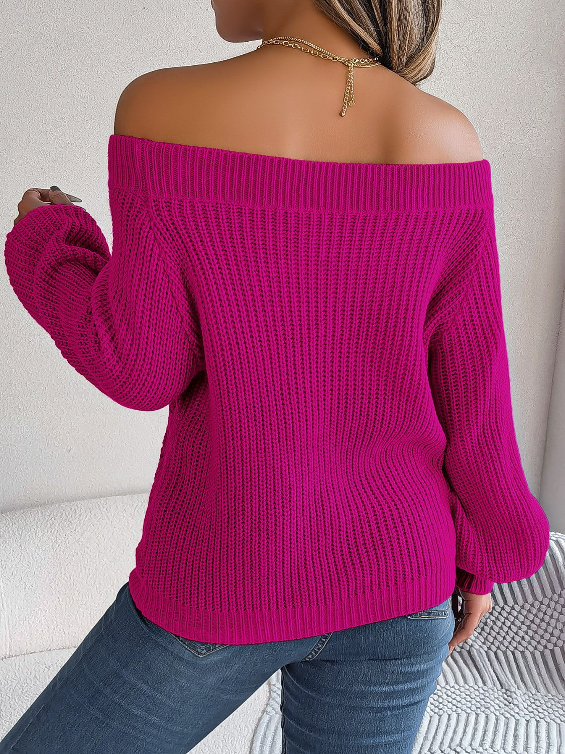 Open-knit off-shoulder sweater in cerise with voluminous sleeves and ribbed texture.
