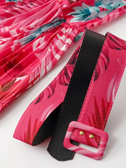 Hot pink pleated midi dress with tropical print and black belt with matching buckle.