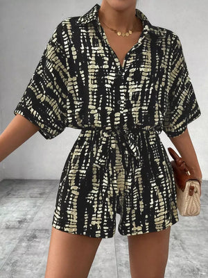 Black and cream abstract print belted romper with collared button-front top and short sleeves.