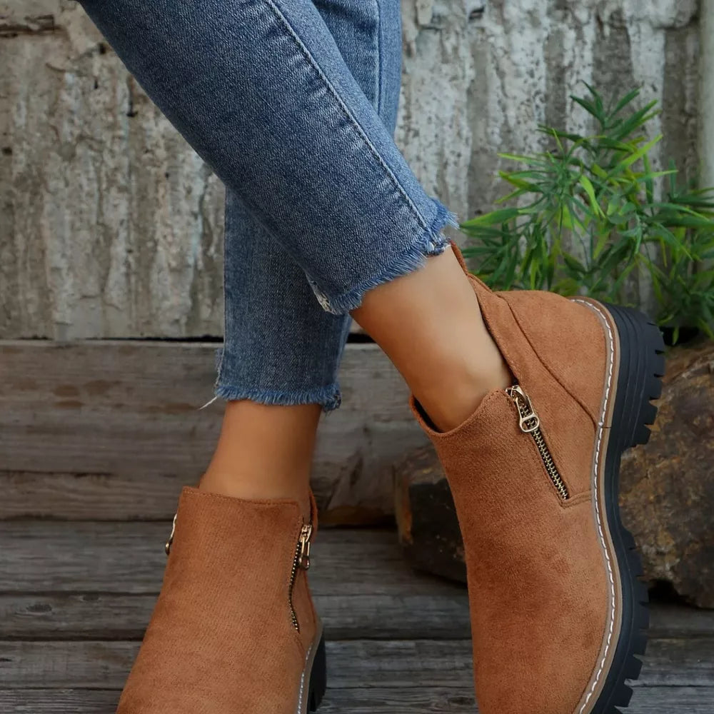 Brown suede ankle boots with side zipper and rugged sole.