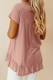 Textured peplum blouse in dusty pink with ruffled hem and short sleeves.