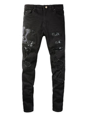 Black skinny jeans with distressed details and embroidered cobra graphic.