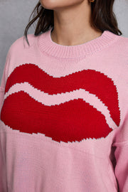 Blush pink knit sweater with a large red kiss graphic and distressed hem.