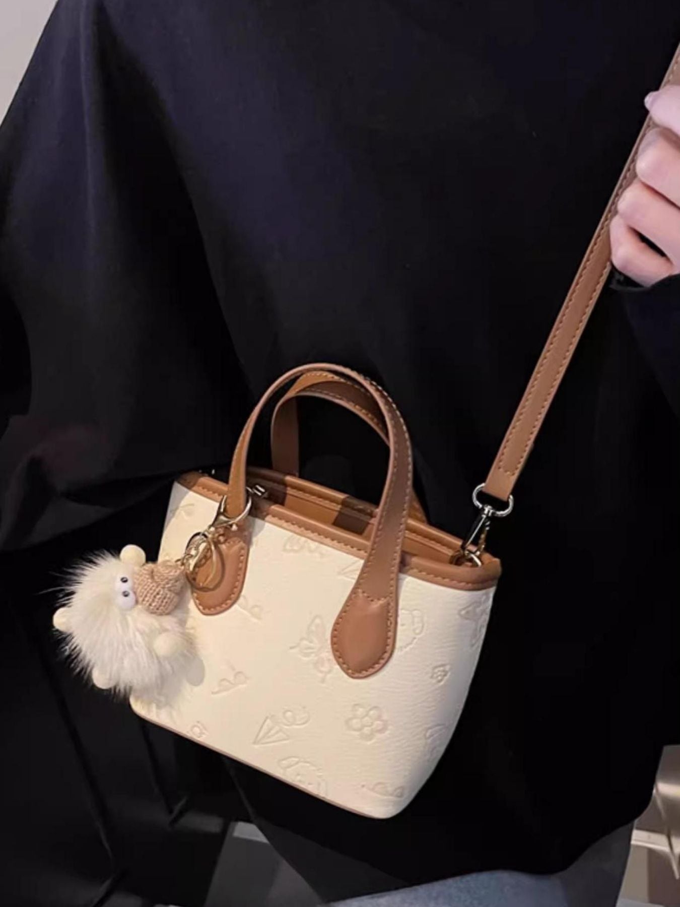 Mini crossbody bag in cream embossed PU leather with brown trim and a fluffy charm.