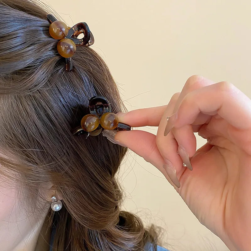 Brown resin orb hair claw clip with acrylic beads, styled in dark hair.
