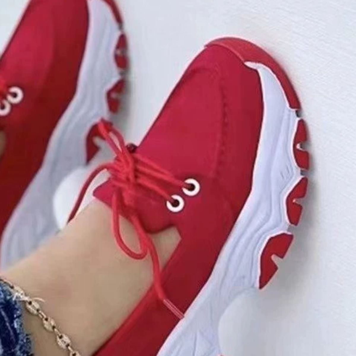 Red lace-up sneakers with white chunky sole and round toe.