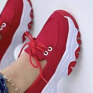 Red lace-up sneakers with white chunky sole and round toe.
