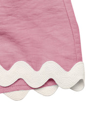 Pink maternity romper cover-up with white scalloped trim detail.