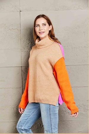 Colorblock turtleneck sweater with asymmetric hem in khaki, rust, and pink with orange sleeves.