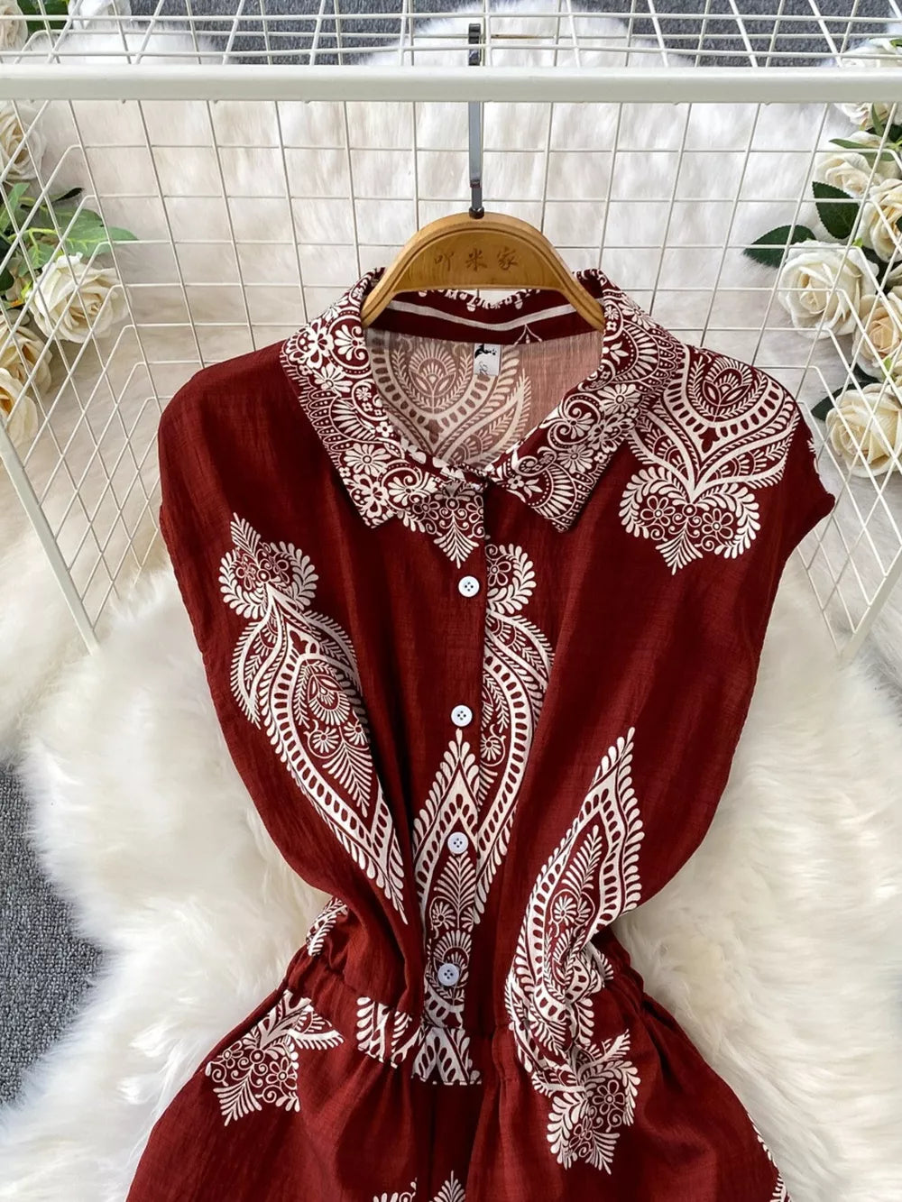 Wine red buttoned romper with white paisley print, collared neckline, and short sleeves.