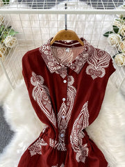 Wine red buttoned romper with white paisley print, collared neckline, and short sleeves.