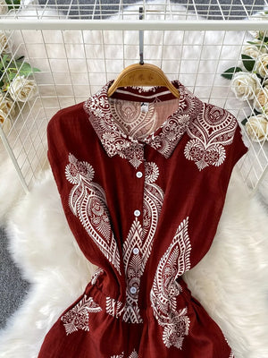 Wine red buttoned romper with white paisley print, collared neckline, and short sleeves.
