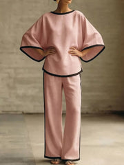 Pink two-piece set with boat neck top and wide leg pants, featuring black contrast trim.