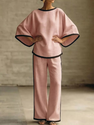 Pink two-piece set with boat neck top and wide leg pants, featuring black contrast trim.