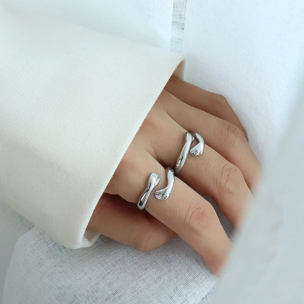 Silver embracing hands open ring, a chic accessory for women.