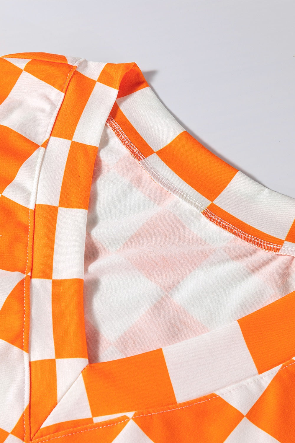 Orange and white checkered V-neck outfit set detail with visible stitching.