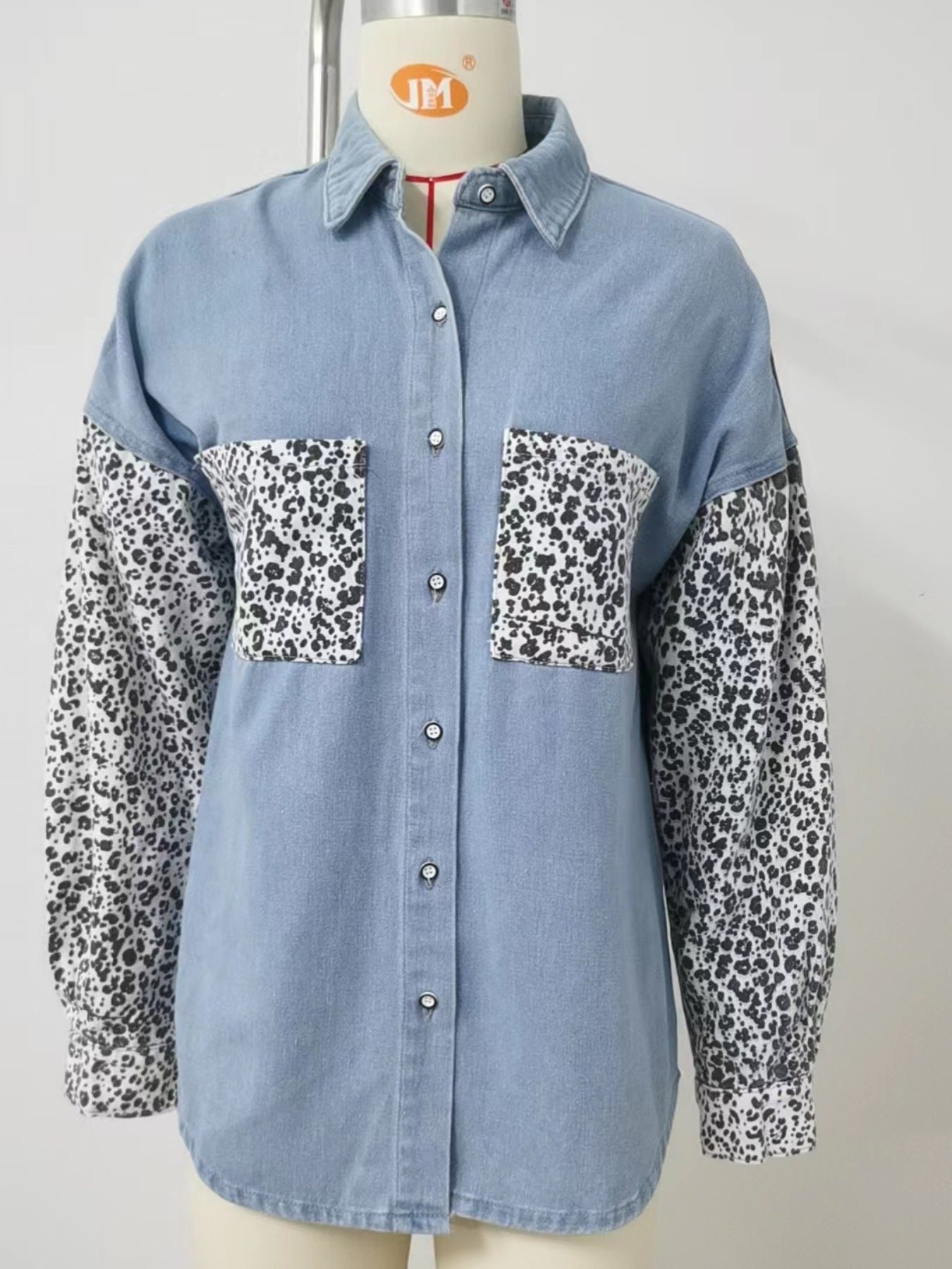 Denim shirt with leopard print sleeves and chest pockets. Button-up style.