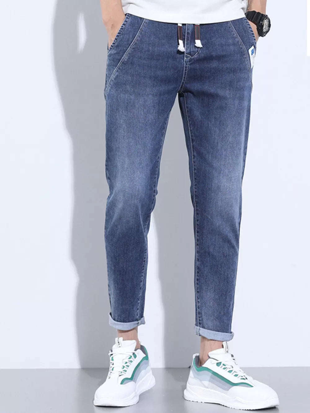Washed skinny jeans in dark blue with adjustable drawstring and cuffed ankles.