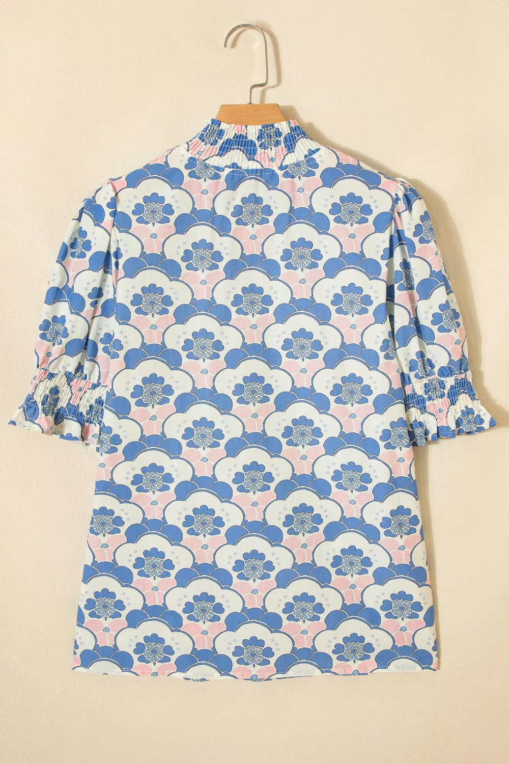 Blouse with floral pattern, high neck, and ruffled cuffs.