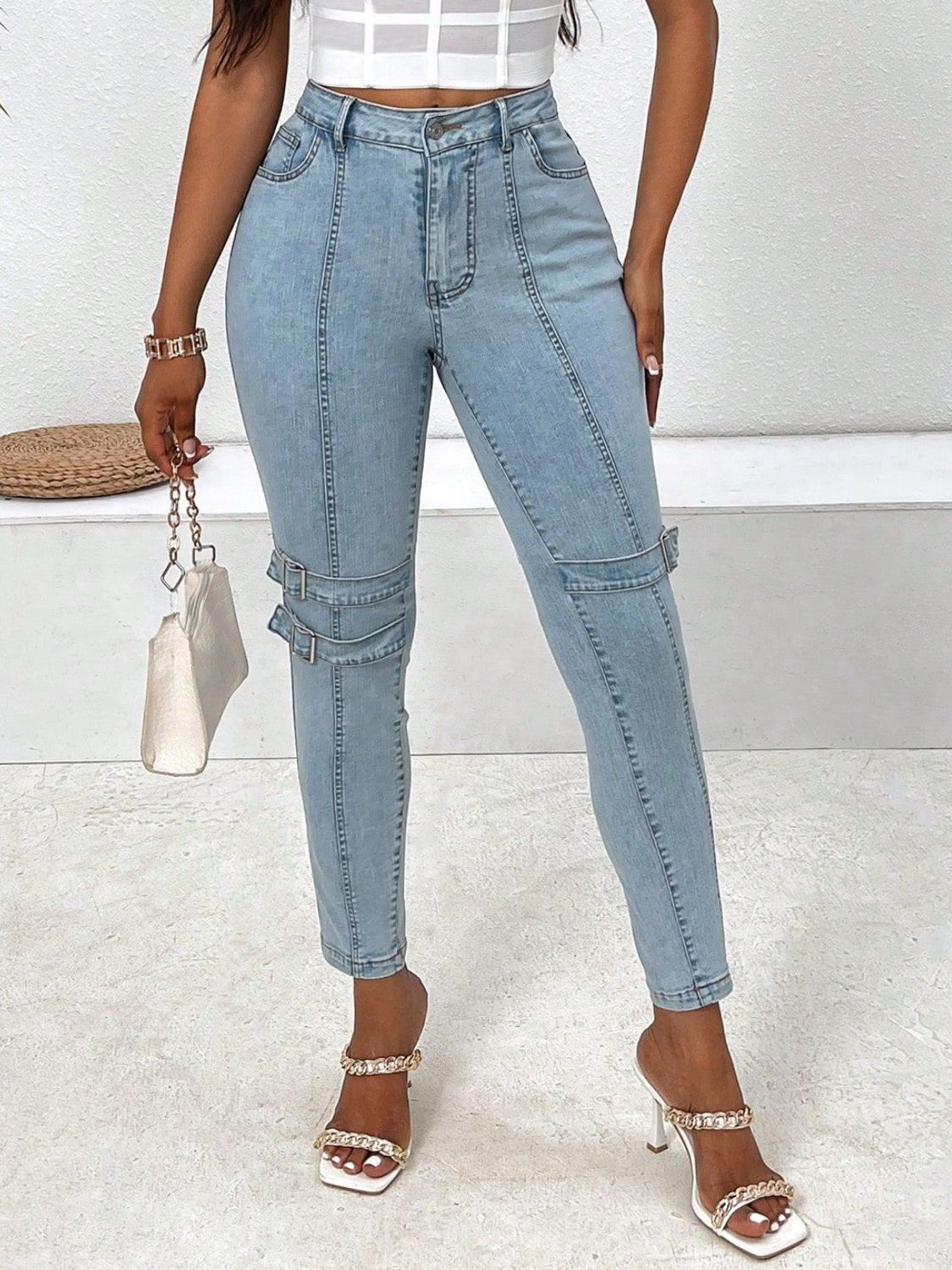 Light wash denim jeans with buckle detail and seam accents.