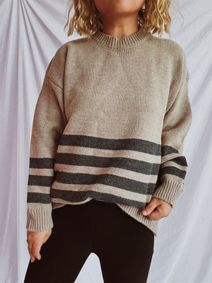 Tan ribbed knit sweater with horizontal dark gray stripes, crew neck, and long sleeves.