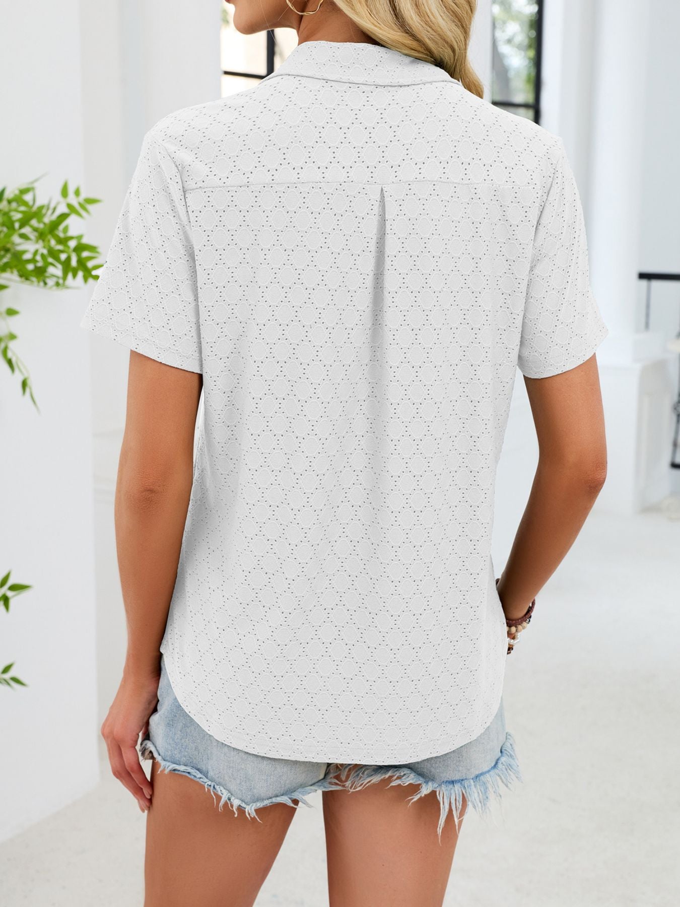 White eyelet polo collar blouse with short sleeves and a back pleat detail.