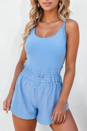 Light blue tank romper with gathered drawstring waist and scoop neck.