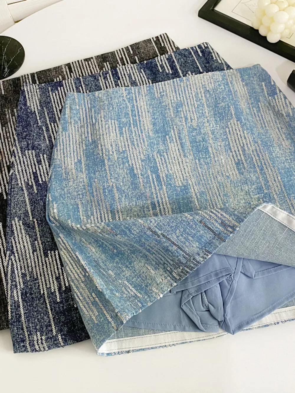 Light blue sequin mini skirt with vertical stripe pattern and zipper detail.