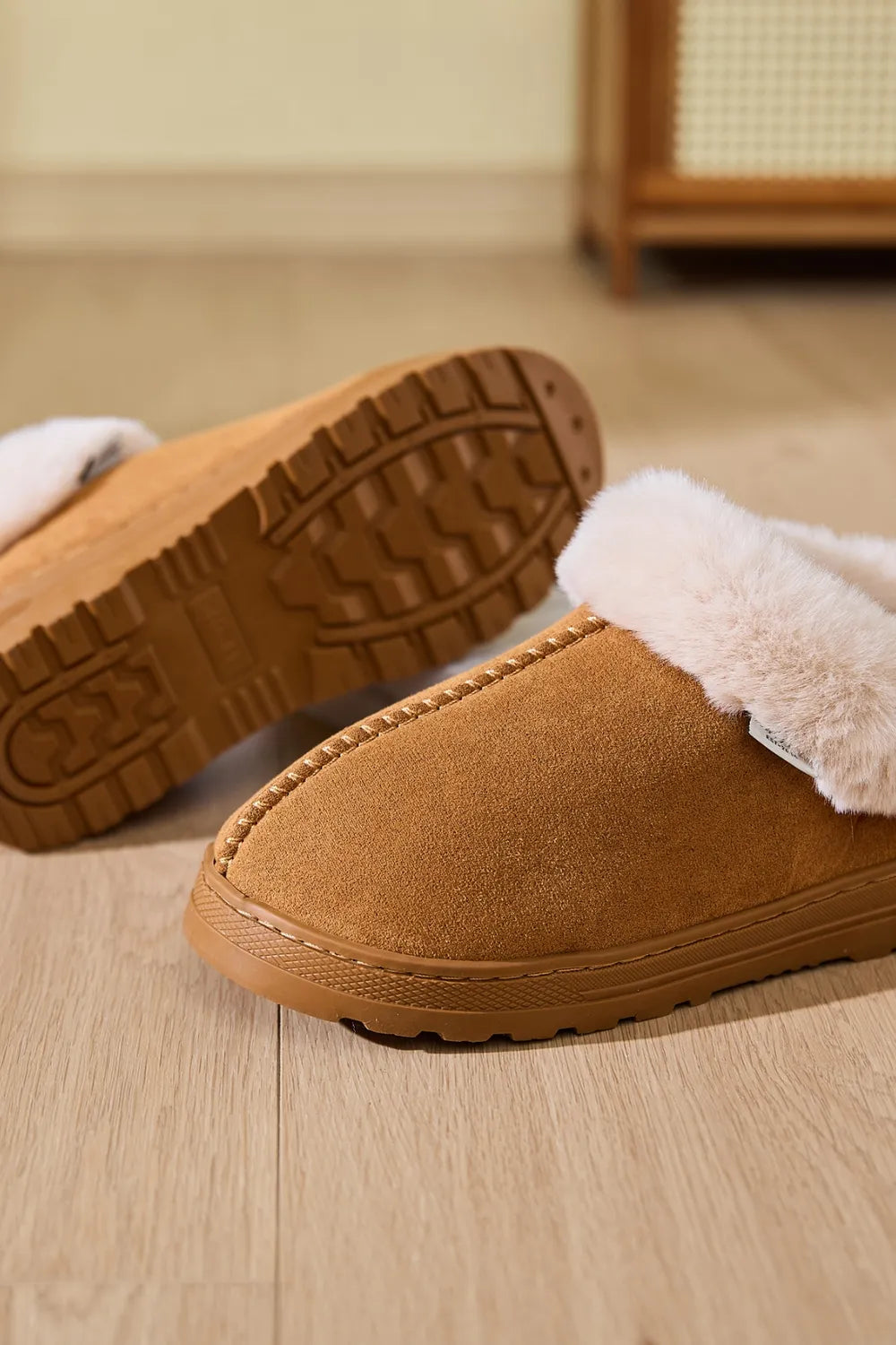 Caramel suede slippers with plush shearling trim and stitched detail.