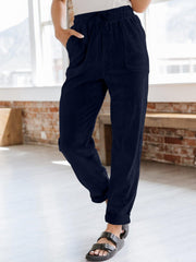 Navy corduroy tapered trousers with drawstring waist and pockets.