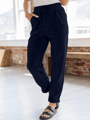 Navy corduroy tapered trousers with drawstring waist and pockets.
