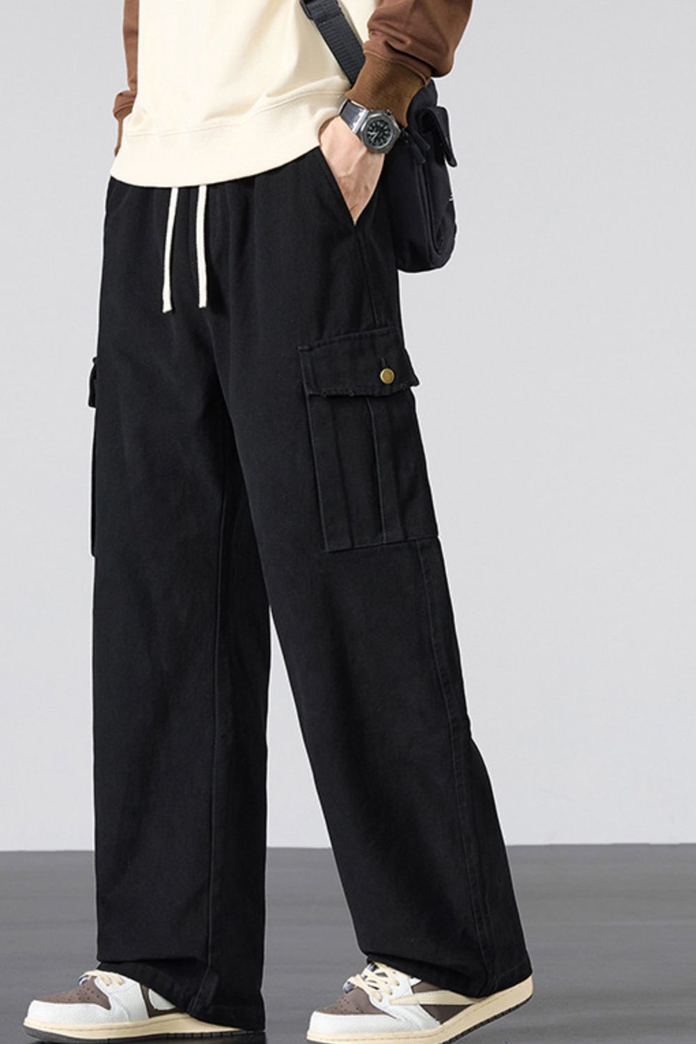 Black relaxed fit cargo sweatpants with drawstring and button-flap pockets.