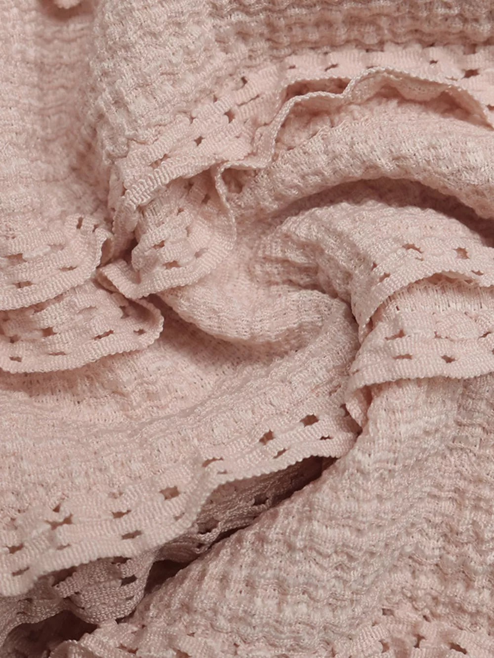 Pink textured halter romper with ruffled lace trim and eyelet details.
