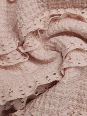 Pink textured halter romper with ruffled lace trim and eyelet details.
