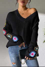 Black v-neck sweater with colorful crochet granny square sleeve details, 100% acrylic knit.