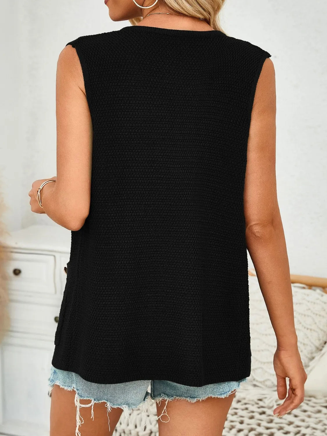 Black buttoned knit vest with textured pattern and side button detail.