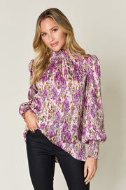 High neck abstract print blouse in red-violet with long puff sleeves and smocked cuffs.