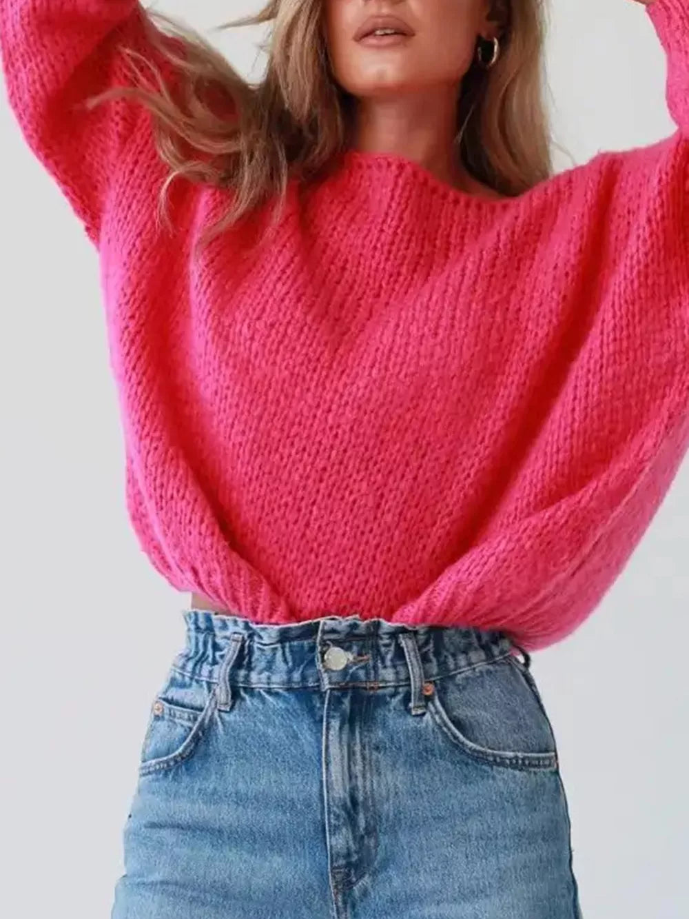 Hot pink chunky knit sweater with boat neck and oversized balloon sleeves, styled with denim.