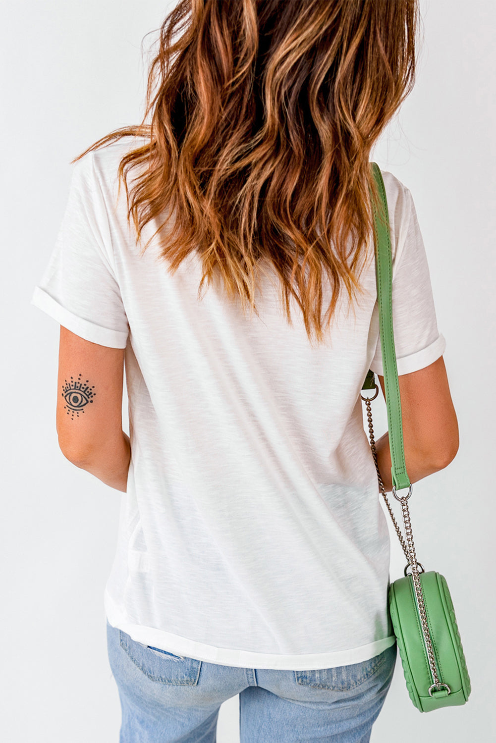 White casual t-shirt with rolled sleeves and a faded graphic print on the arm.