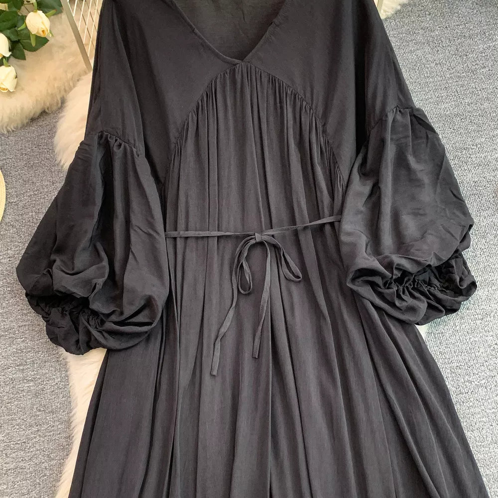 Black bohemian maxi dress with V-neck, cinched waist tie, and voluminous balloon sleeves.