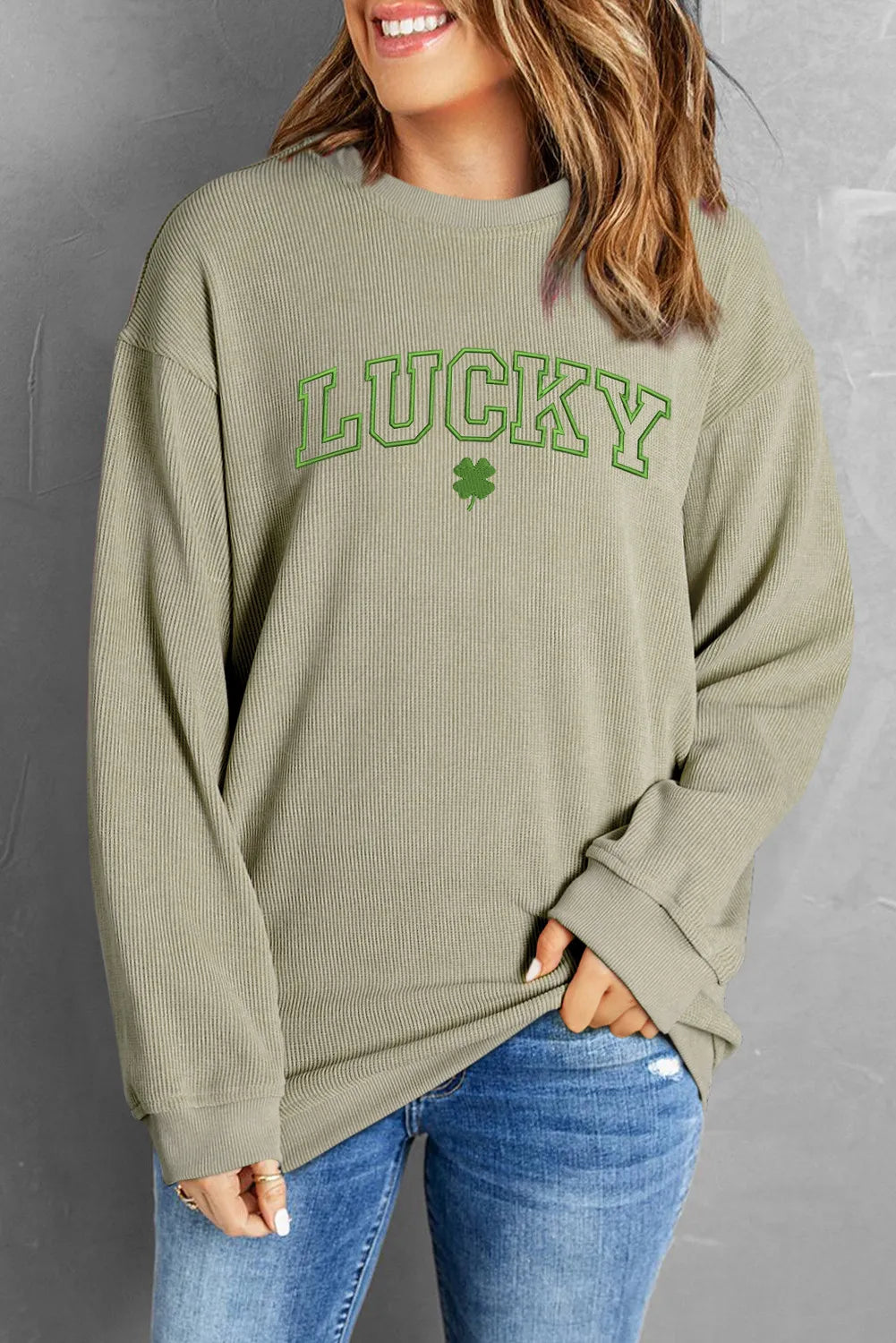 Light green textured ribbed crewneck sweatshirt with "Lucky" graphic and clover detail.