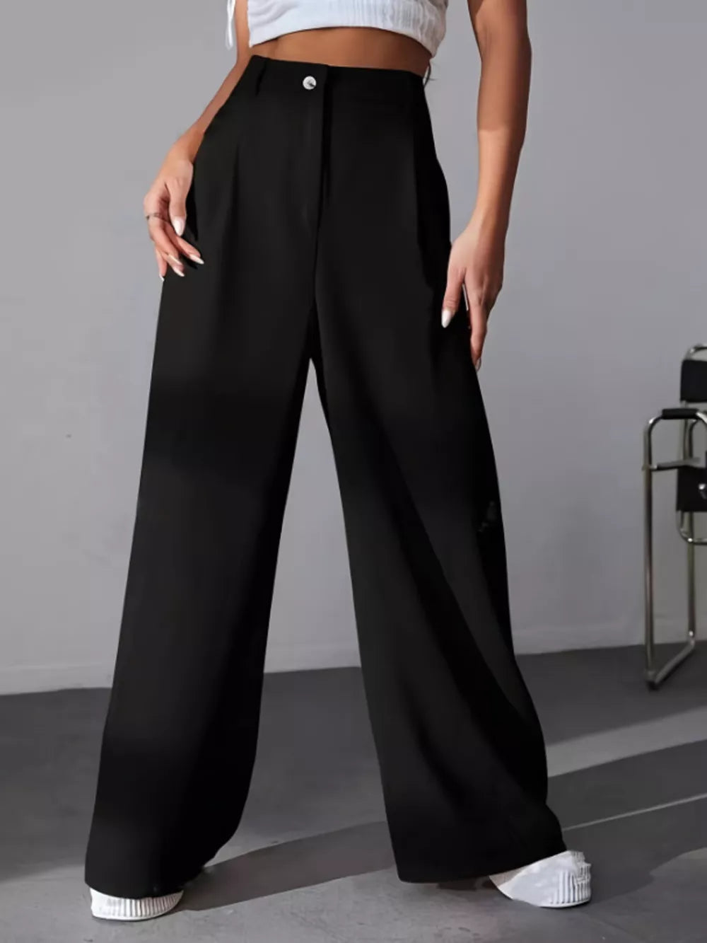 Black high-waisted pleated wide-leg maternity trousers with button detail.