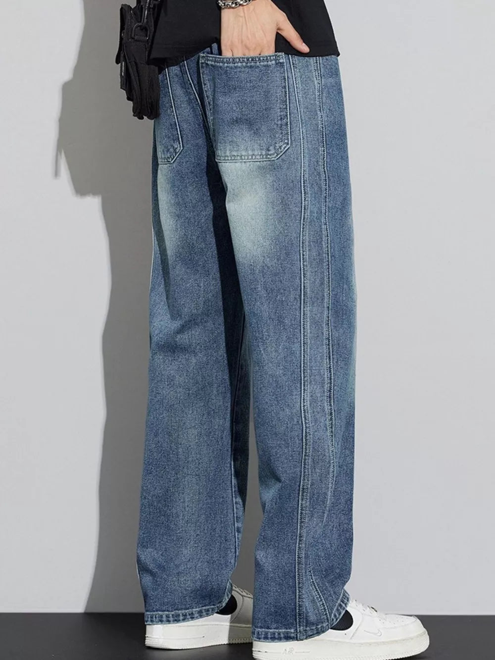 Men's blue wide-leg jeans with drawstring detail and visible stitching.
