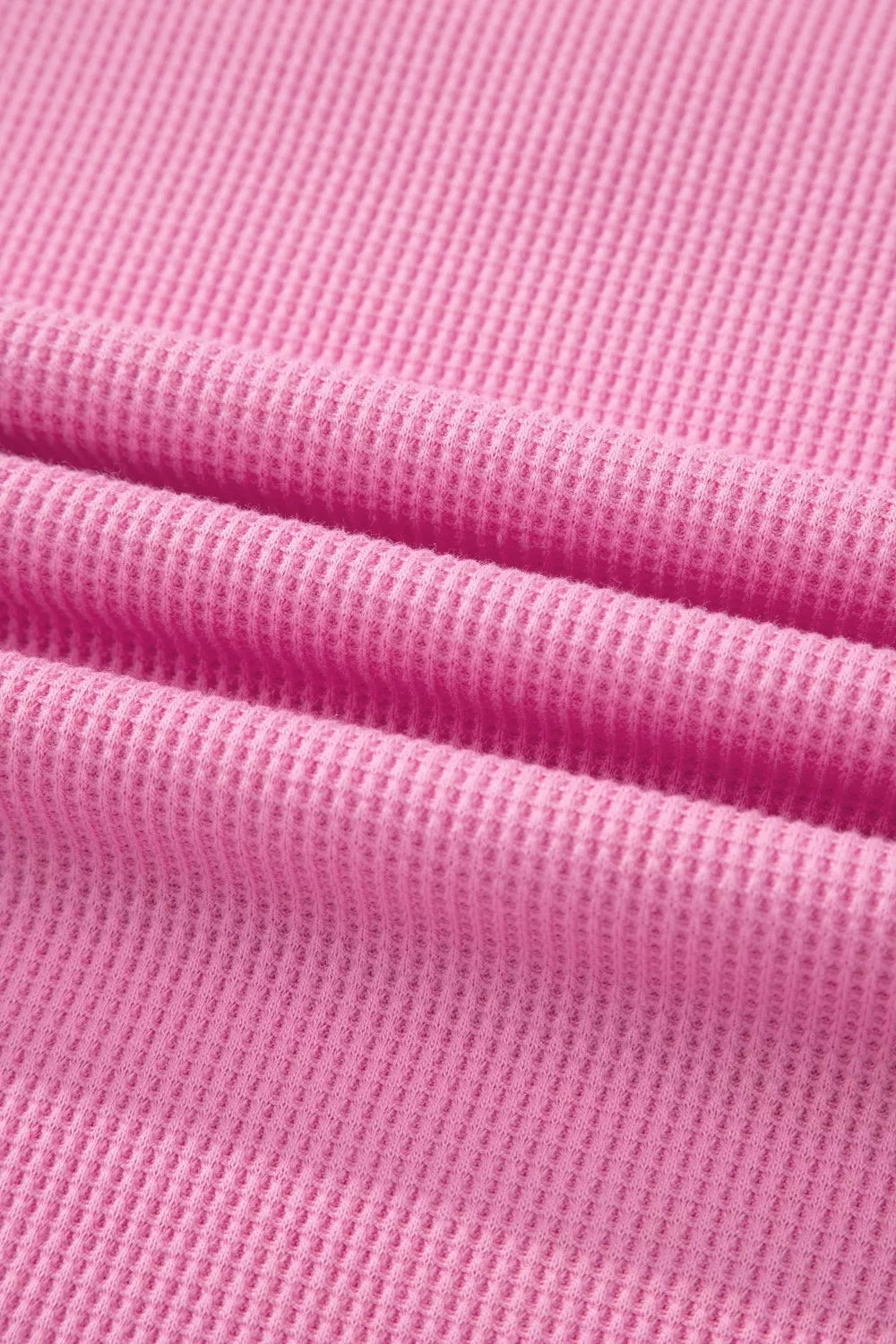 Pink waffle knit polyester t-shirt with a pocket detail and textured fabric.